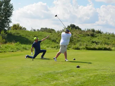 Sunny Summer Day, two golfers at a tee, one in mid swing