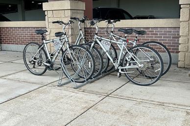 Four place bicycle rack outside on concrete with 4 touring bikes facing each other, 2 on either side