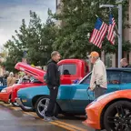 Classic late 60s Camaro sitting next to a newer Corvette two men chatting in between