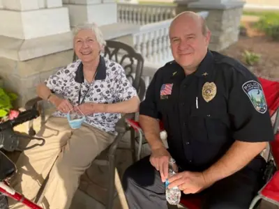 An elderly Caucasian woman on left and Caucasian male, former Police Chief Katers right sitting on a porch 