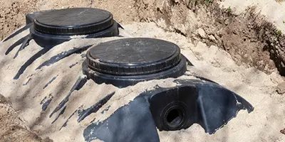 Septic tank partially buried in sand