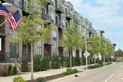 American flags waving off of light poles in front of an apartment building