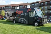 Photo of the Pizza Barn Food Truck siting on a grassy area by The Draw Amphitheater