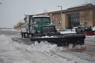 A snow plow truck pushing a mound of snow to the side of the road