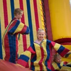 Two young children (boy and girl) wearing Velcro jackets trying to stick themselves to a wall