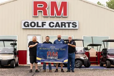 Four men holding Business of the Year RM Golf Carts banner