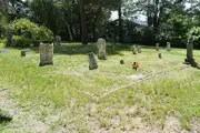Trott Brook Cemetery, summer, numerous very old headstones open area with trees in distance 