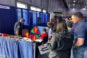 Families interact with fire department booth, spinning prize wheel and viewing safety demos.