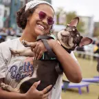 A woman with a wide smile holding her Boston Terrier