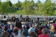 Four member band dressed in black suits on stage, with an audience in the foreground