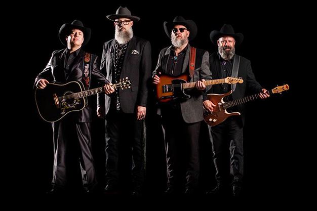 Four male members of a band with instruments, wearing semi-formal western wear, cowboy hats