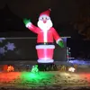 Snow-covered ground, massive inflatable lit Santa in front of side of a metal pole building