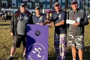 Four Caucasian men in baseball caps standing behind an Anytime Fitness cornhole board