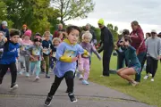 Little boy out in front in the Youth fun run with more children starting behind them