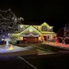 Two-story with porch and garage on left, trees and holiday decorate in lights