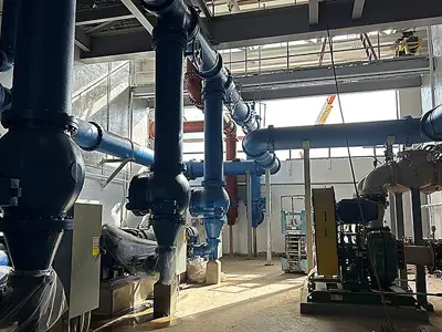 Three huge water pumps with various piping coming off them catwalk above