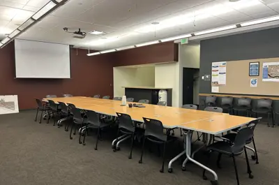 Meeting room with long table surrounded by chairs, kitchenette on the right