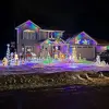 Two-story house with garage on right, yard and home totally encased in holiday lights