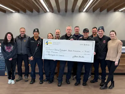 A group of 11 people, some firefighters holding up a giant check for $5,000