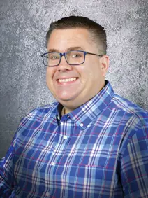 Council member Dan Specht smiling, buzz cut, glasses wearing a plaid shirt