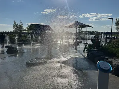 Splash Pad, water spraying upwards from with the sun behind it