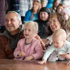 An older man and woman sitting with young children on their laps at a table