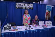 Color City Pottery staff smiling behind a table with pottery pieces & promo items at their booth