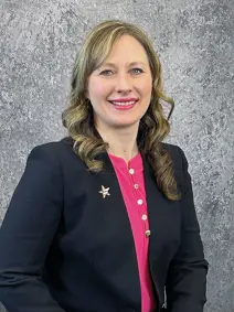 Council member Shanna Stewart, smiling, has long hair, wearing a blazer