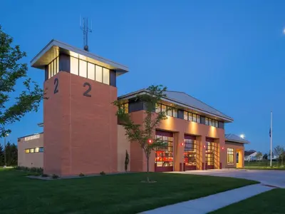 Fire Station 2 at dusk a tower on the left side building has 3 large overhead doors