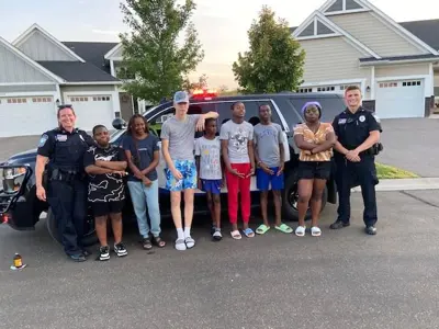 9 people standing in a row front of a Ramsey Police SUV, two police officers on either end