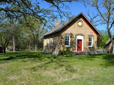 Smaller gable roof brick building with a door in the center and two window flanking on either side