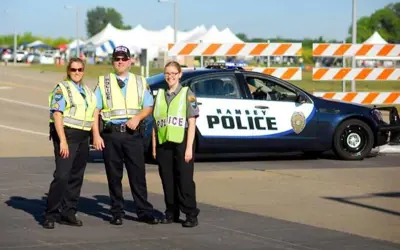 Police Reserves and Explorer outside wearing traffic vest standing in front of a police car. 