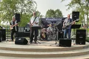 Roadhouse Blue on stage outside at the Draw, three guitar players, one drummer