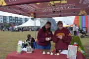 Two UMN Extension ladies holding garlic behind a table with printed materials on it